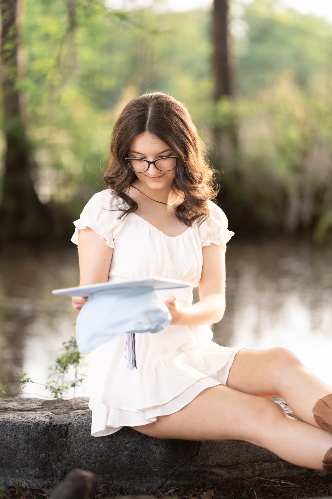 Graduate portrait reading beside a pond